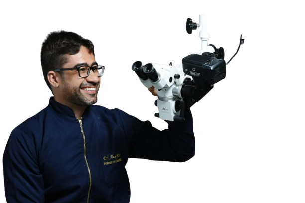 Dr. Alex Brito com braços cruzados ao lado de microscópio odontológico